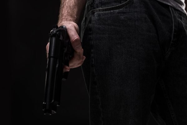 killer-with-gun-black-background-studio-scaled.jpg